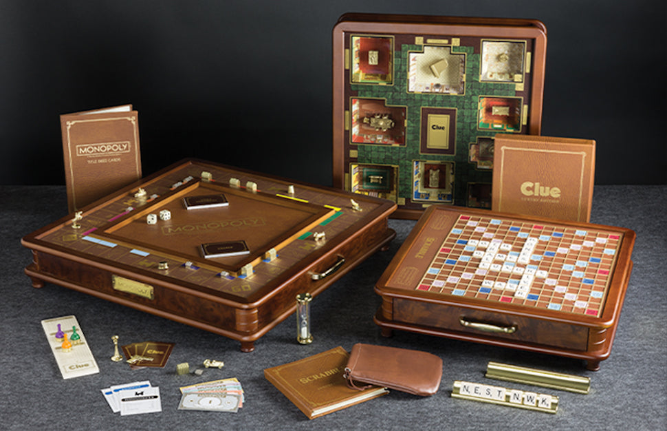 WS Game Company Luxury Edition trio: Monopoly, Scrabble, and Clue in heirloom-quality wood cabinets with gold accents.