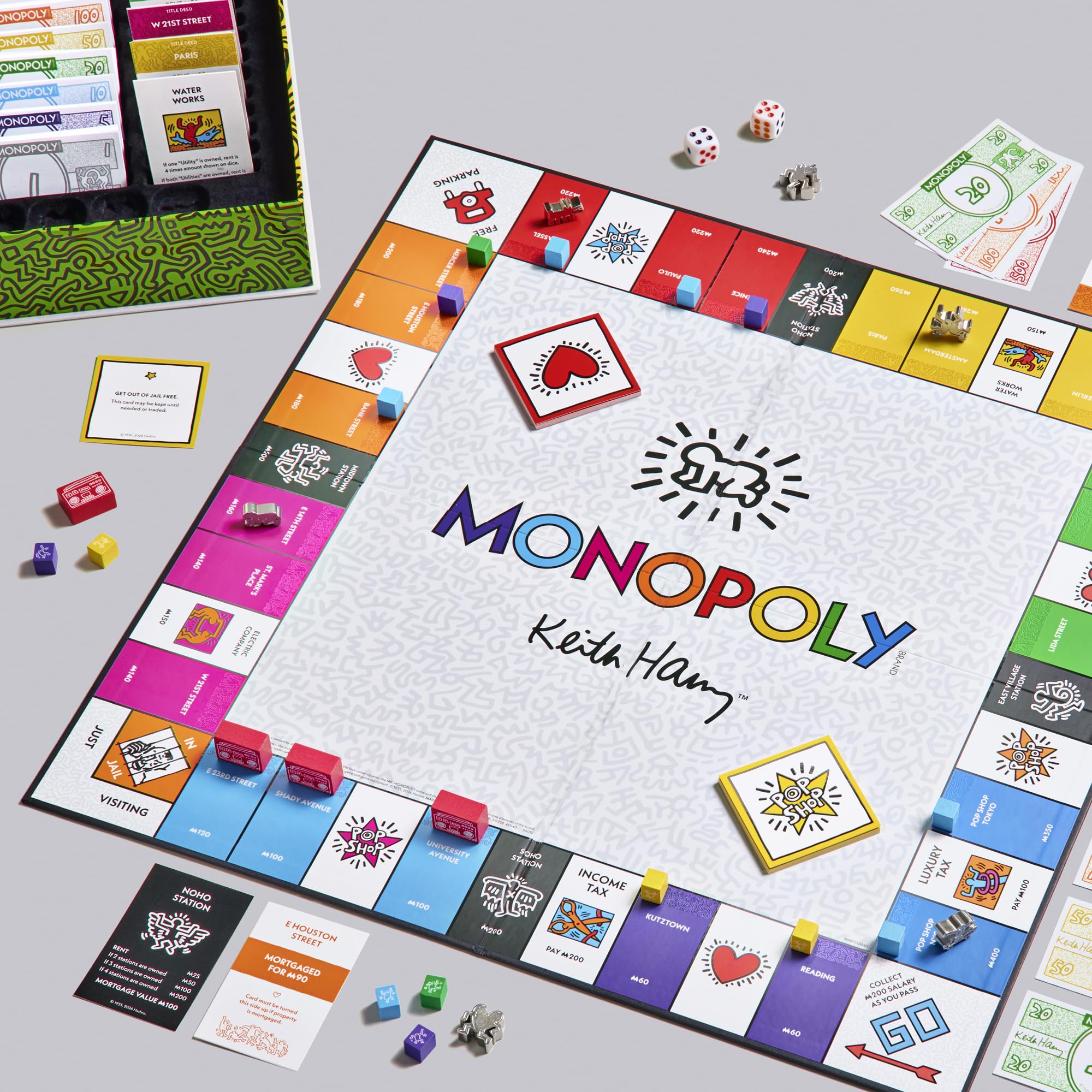 Monopoly board game with colorful properties and game pieces on a gray surface.